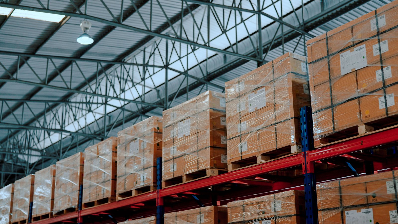 Shelves Partially Filled With Boxes And Crates Of Finished Goods In A Warehouse.